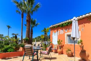 een terras met een tafel, stoelen en palmbomen bij Quinta dos Amigos in Almancil