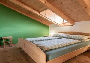 Cama grande en habitación con pared verde en Plazores, en San Vigilio Di Marebbe