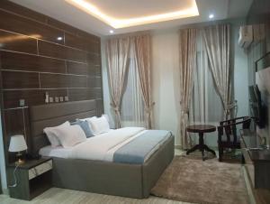 a bedroom with a bed and a table and a desk at Walijam Bloom Luxury Suites in Kaduna