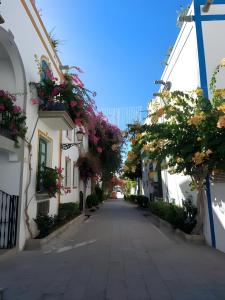 an empty street with flowers on the buildings at Vv Velero in Puerto de Mogán +13 photos