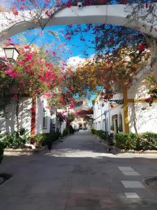 an empty street with white houses with flowers at Vv Velero in Puerto de Mogán