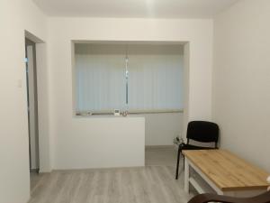 a room with a table and a chair and a white wall at Apartament Milcov in Galaţi