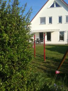 a white house with red poles in the yard at Ferienwohnung Ferienzimmer,nahe Rostock, Bentwisch Ot Albertsdorf bis 7 Personen in Bentwisch