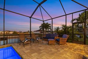 eine Terrasse mit einem Sofa, Stühlen und einem Pool in der Unterkunft The Pink Flamingo Sanctuary in Cape Coral