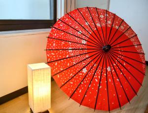 a red umbrella sitting on a wooden floor next to a lamp at D,A-House OSAKA in Osaka +37 photos