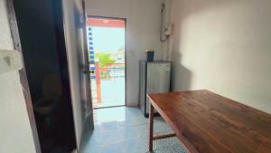 a room with a wooden table and a refrigerator at OYO 75596 The Sirisuk House in Ban Nong Nae