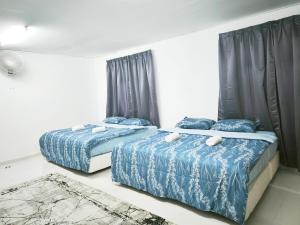 two beds in a bedroom with blue comforter at OYO 91244 Aufa Chalet in Kampong Ru Tujoh