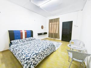 a bedroom with a bed and a table and a chair at OYO 91244 Aufa Chalet in Kuala Terengganu