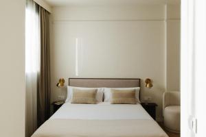 un dormitorio con una cama con sábanas y almohadas blancas en Atipico Madrid, en Madrid