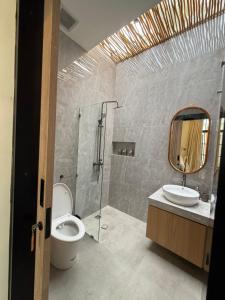 ein Badezimmer mit Toilette, Waschbecken und Spiegel in der Unterkunft Amigo uluwatu in Uluwatu + 4 Fotos