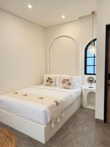 ein weißes Schlafzimmer mit einem großen Bett und einem Fenster in der Unterkunft Amigo uluwatu in Uluwatu
