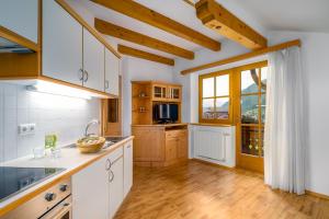 a kitchen with white cabinets and a large window at Wieserhof Vals in Valles +21 photos