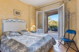 Villa - La Mignonette في كافالير سور مير: غرفة نوم بسرير وكرسي وباب زجاجي منزلق