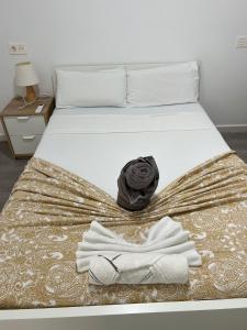 een bed met witte handdoeken en een zwarte roos erop bij Apartamento 2 habitaciones con Terraza Malaga in Málaga