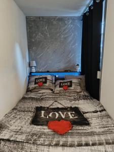 a bed with two pillows with the words love at Studio dans résidence avec piscine à 50m de la mer in Roquebrune-Cap-Martin