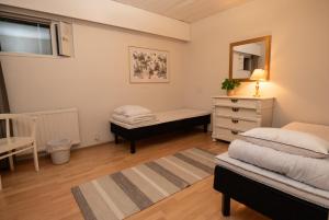 a bedroom with two beds and a dresser and a mirror at Mission Guesthouse in Gäddnäs