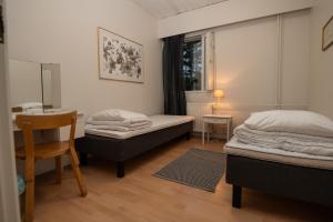 two beds in a room with a table and a chair at Mission Guesthouse in Gäddnäs