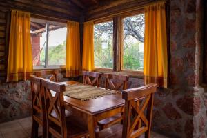 a wooden table and chairs in a room with windows at Cabañas en Nono La Soñada in Nono +28 photos