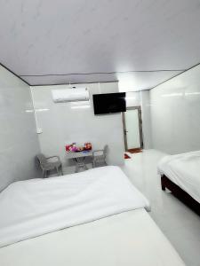 a white room with two beds and a tv at Vinh Hotel in Thốt Nốt