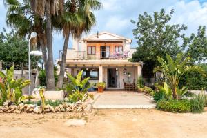 a house on the beach with palm trees at Alegrías in Pla de na Tesa