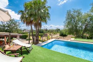 a swimming pool with a table and chairs next to a villa at Alegrías in Pla de na Tesa