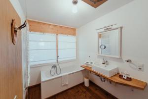 a bathroom with a sink and a tub and a window at Hotel Am Fichtelsee in Fichtelberg +60 photos