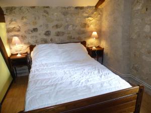 a bed in a bedroom with two lamps on tables at Le petit moulin in Journet