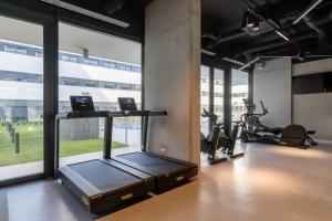a gym with a treadmill and ellipticals in a room with windows at Student Experience Granada - Luxury Hostel in Granada
