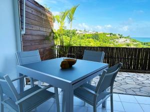 a blue table and chairs on a balcony with the ocean at L'écrin des Salines, votre escale tropicale in Le Gosier +27 photos