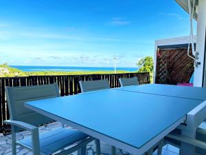 a blue table and chairs on a balcony with the ocean at L'écrin des Salines, votre escale tropicale in Le Gosier