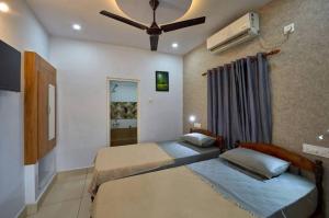 a bedroom with two beds and a ceiling fan at The Panakal Boho in Cochin