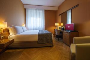a hotel room with a bed and a desk with a computer at Exe Majestic in Naples