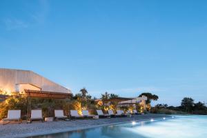 a hotel with a swimming pool and lounge chairs at Pa.te.os in Melides