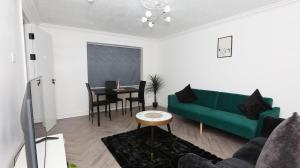 Una sala de estar con un sofá verde y una mesa. en Modern 3 bed house in Edmonton with private driveway parking, en Edmonton