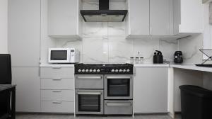 cocina blanca con fogones y microondas en Modern 3 bed house in Edmonton with private driveway parking, en Edmonton