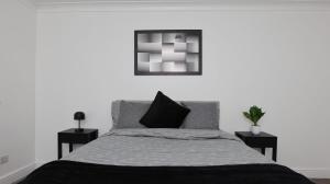 Un dormitorio con una cama con dos mesitas de noche y un cuadro. en Modern 3 bed house in Edmonton with private driveway parking, en Edmonton 10 fotos más