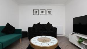 una sala de estar con un reloj frente a un sofá en Modern 3 bed house in Edmonton with private driveway parking, en Edmonton