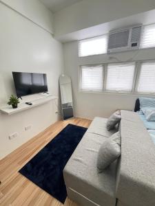een slaapkamer met een bank en een flatscreen-tv bij Holly's Place by Motorists Transient House in Biñan