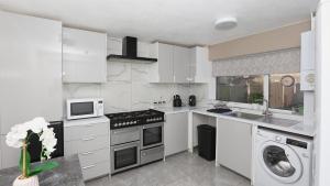 Una cocina con gabinetes blancos y un horno de estufa. en Modern 3 bed house in Edmonton with private driveway parking, en Edmonton