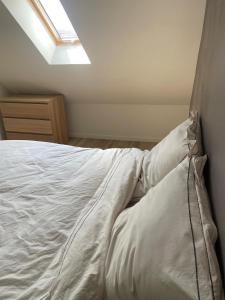 a bedroom with a bed with white sheets and a skylight at Charming House in Beauvais in Beauvais
