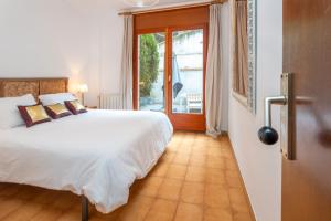 a bedroom with a large white bed and a window at Apartamento con Jardin y Parking in Platja  d'Aro