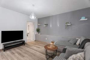 een woonkamer met een bank en een flatscreen-tv bij 4 Apartamentos Omanai Tenerife Sur in Las Galletas