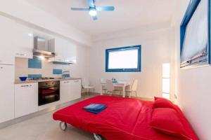 スコリッティにあるBilocale Scoglitti nei luoghi di Montalbanoの白いキッチン(赤いベッド1台付)が備わる客室です。