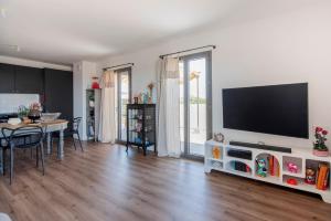 a living room with a table and a television on a wall at 2 bedroom Sun & Terrace with sea view in San-Nicolao