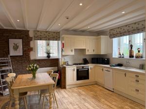a kitchen with white cabinets and a table with chairs at The Gatehouse at Pudleston Court in Hatfield +18 photos