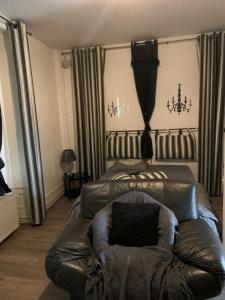 a living room with a leather couch and a bed at Appartement Au Quai 1921 in Besançon