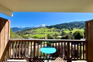 een balkon met een tafel en uitzicht op de bergen bij Bright apartment with Mont Blanc view in Combloux