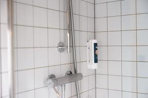a shower head in a white tiled bathroom at The People Lyon Hostel in Lyon +43 photos