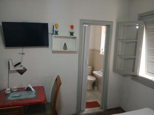 a bathroom with a toilet and a television on the wall at Aconchego do Lar Centro BH Apto 633 Rua da Bahia 187 in Belo Horizonte