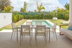 a patio with a table and chairs next to a swimming pool at Serenity Pool Villa at Azuri in Roches Noires